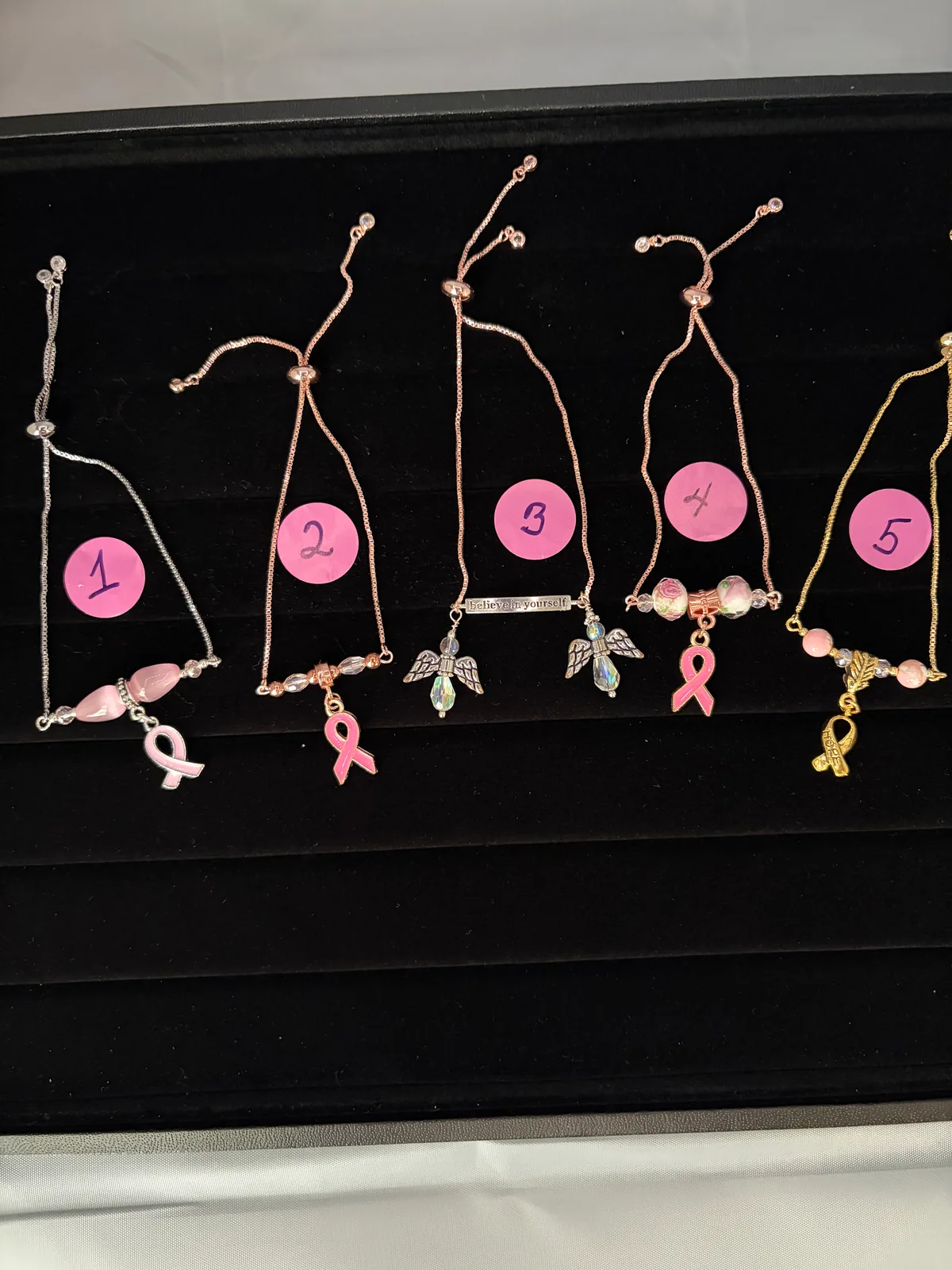 Tray of pink ribbon charm bracelets handcrafted by Patty